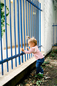 Side view of girl standing against railing