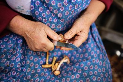 Midsection of woman cutting mushrooms at home