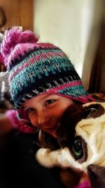 Close-up of smiling girl wearing knit hat with toy at home