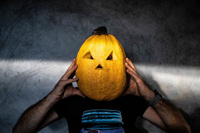 Rear view of man with pumpkin against wall