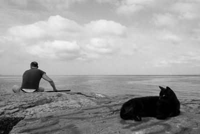 Woman with dog on beach against sky