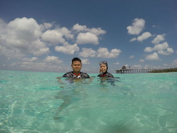 Portrait of man and woman in sea against sky