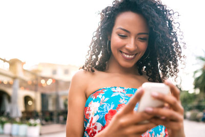 Portrait of smiling young woman using mobile phone