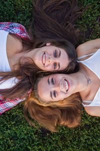 Portrait of smiling female friends lying down on field