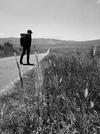 Rear view of man standing on field against sky