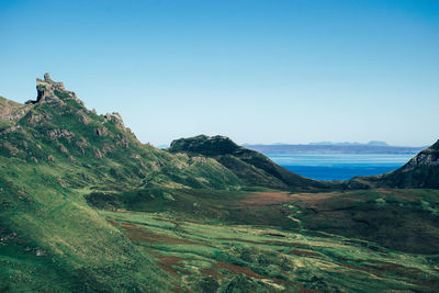 Scenic view of sea and mountains against clear blue sky