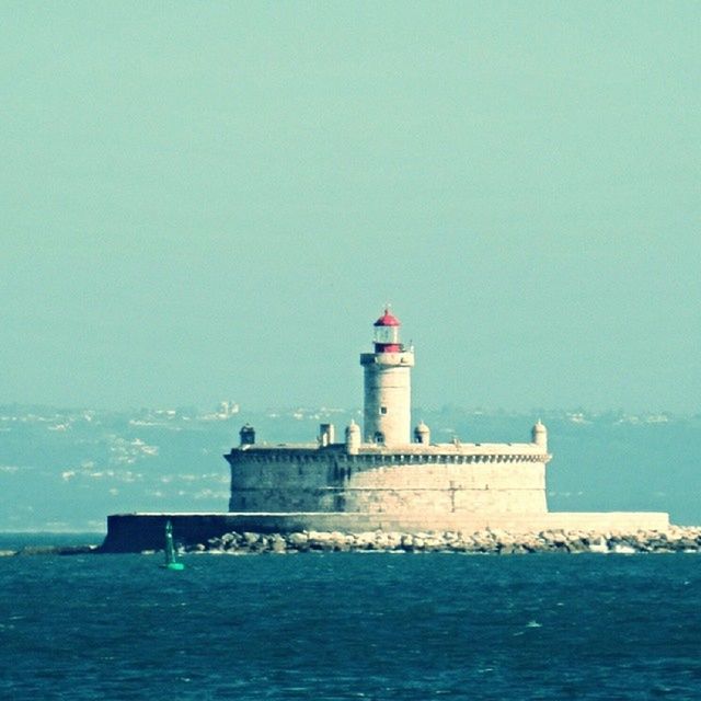 lighthouse, sea, guidance, water, architecture, built structure, building exterior, protection, direction, waterfront, safety, blue, horizon over water, security, copy space, clear sky, tower, sky, rippled, day