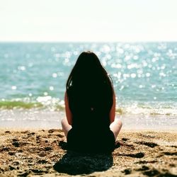 Rear view of woman sitting on beach