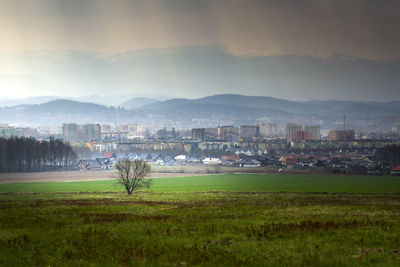 Scenic view of field and townscape against sky