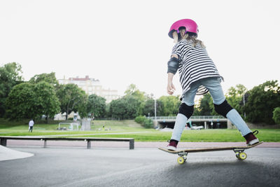 Full length of girl skateboarding at park against clear sky
