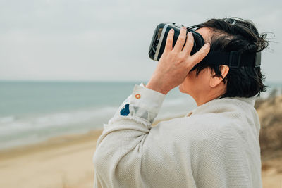 Close-up portrait adult woman on a sandy beach in spring wearing vr virtual reality glasses in front