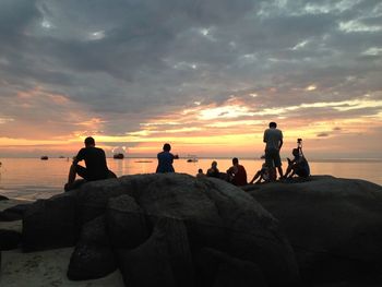 Silhouette of people on beach at sunset