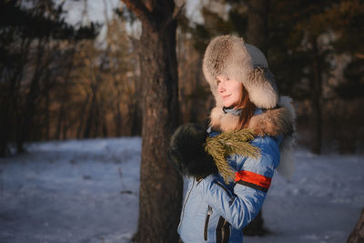 Close-up of woman standing on snow field amidst trees