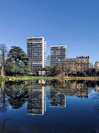 Reflection of buildings in lake against blue sky