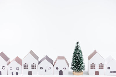 Close-up of christmas tree and model homes against white background