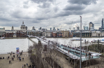 High angle view of buildings by river against cloudy sky