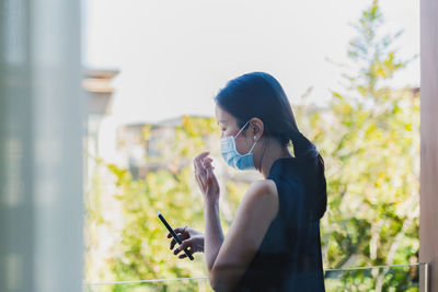 Woman in medical mask using smart phone