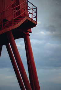 Low angle view of metallic structure by sea against sky