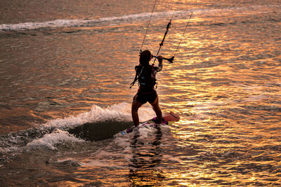 High angle view of man kiteboarding on sea during sunset