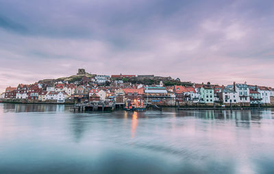 View of townscape by river against sky