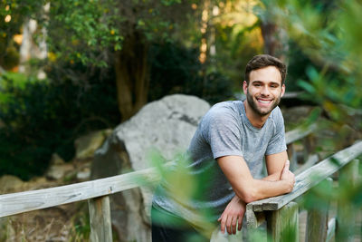 Portrait of young man sitting on wood