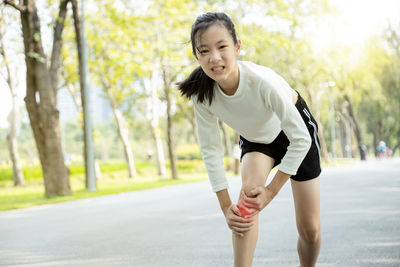 Full length of young woman running on road