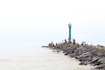 People on grayon at beach against clear sky