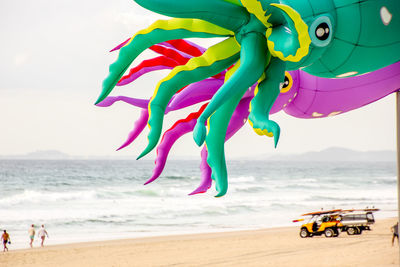 Multi colored toy on beach against sky