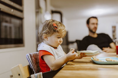 Mother and daughter sitting on table at home