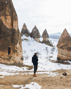 Rear view of woman standing on snowcapped mountain against sky