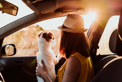 Side view of woman with puppy looking through window in car