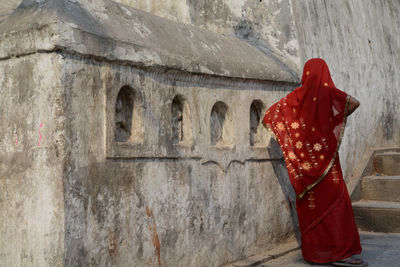 Rear view of woman standing against red wall