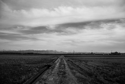 Railroad tracks on field against sky