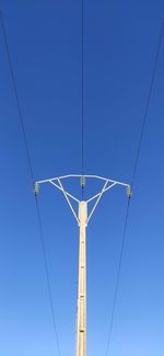 Low angle view of power lines against clear blue sky