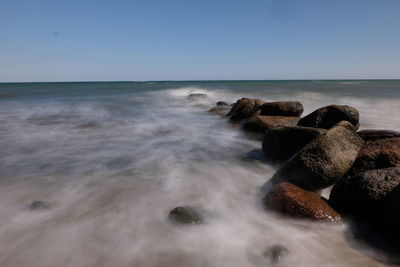 Scenic view of rocks on sea against sky