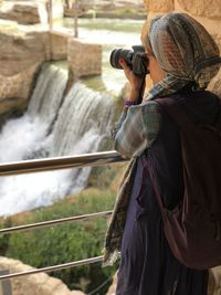 Rear view of woman photographing while standing on field