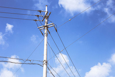 Low angle view of electricity pylon against blue sky
