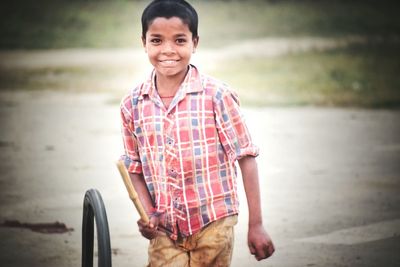 Portrait of boy playing with tire on footpath