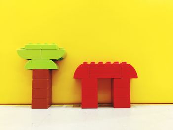 Close-up of plastic toys on floor against yellow wall