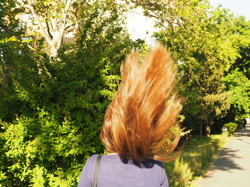 Rear view of woman with tossing hair in park