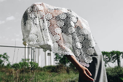 Side view of young woman covered with scarf against sky