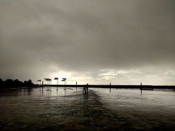 Silhouette man on pier over sea against sky during sunset