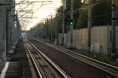 Empty railway tracks at sunset, forest on background. perspective of electrified high-speed railroad