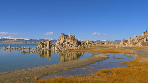 Panoramic view of rocks on shore against clear blue sky