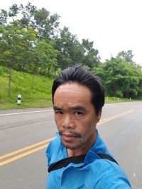 Portrait of man on road against trees