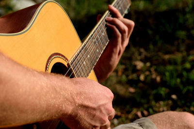 Midsection of man playing guitar