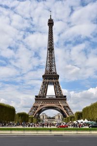 Group of people in front of tower against cloudy sky