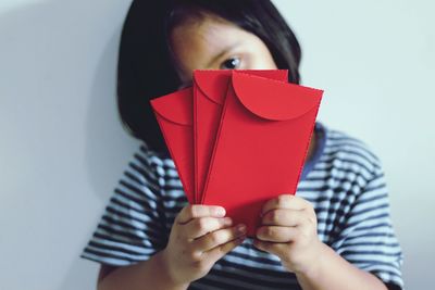 Close-up of girl holding red envelopes