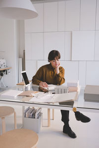 Full length of upholstery worker sitting at desk in store