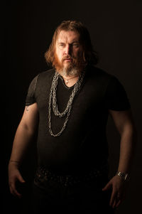 Portrait of young man standing against black background